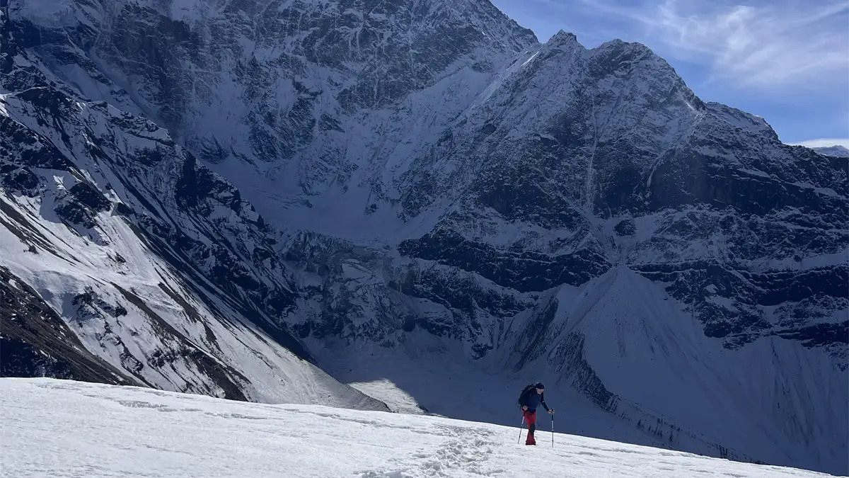 Climber ascending high on Manaslu with summit ridge behind — Nepal Himalaya