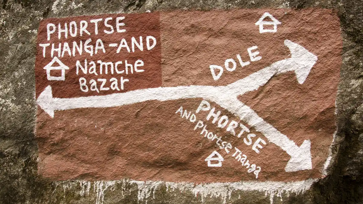 Hand painted trail sign showing directions to Namche Bazaar Phortse and Dole in Khumbu
