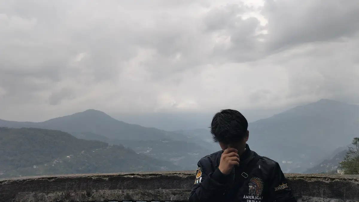 Confusion was my first teacher. Rachit standing thoughtfully at his home overlooking misty mountains, reflecting on childhood learning and personal growth.