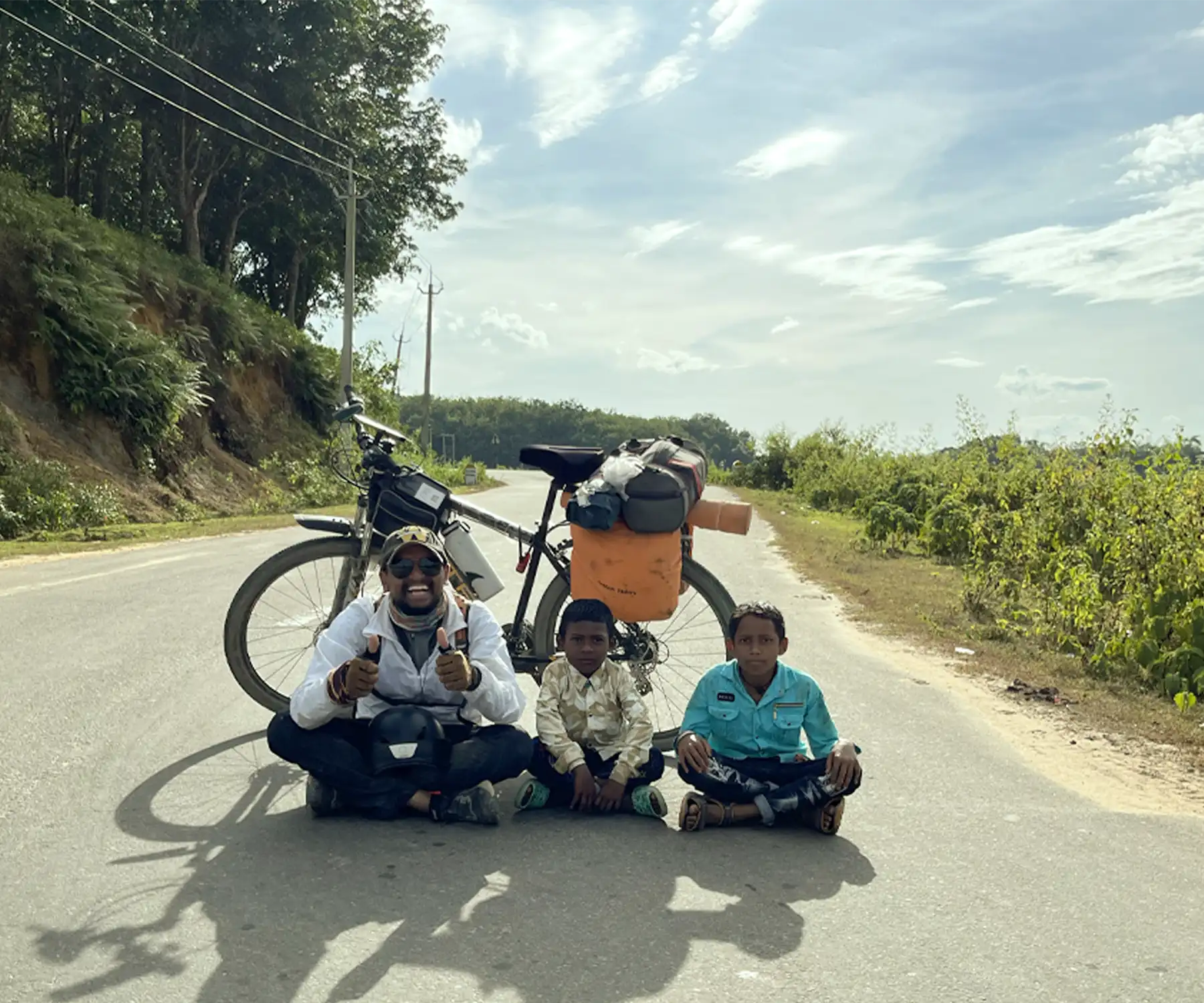 Venky with his loaded touring bicycle and two local children on an open road in India